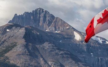 SCC updates requirements for accreditation of standards development organizations Canadian flag in front of scenic mountain.