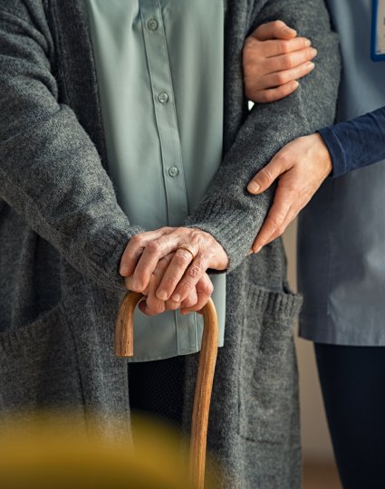 health care worker helping elderly person walk